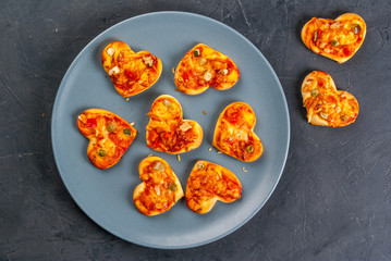 Romantic foods for Valentine's Day. Miniature pizza at one bite, cheese and fresh vegetables, close view, copy space, top view