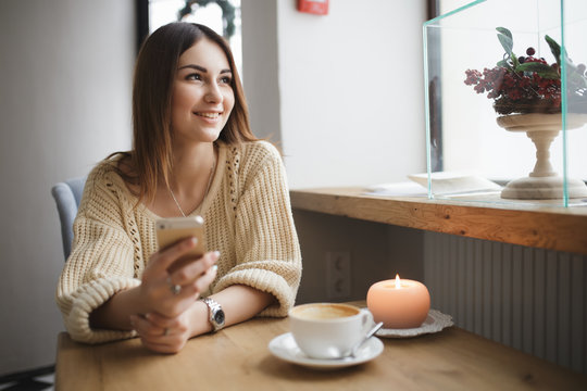 Cute Woman Using Her Smartphone In A Coffee Shop