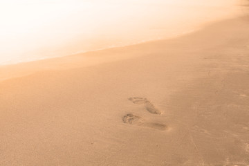 Blurry background of beach and sea waves with feet stamp on sand, Vintage color style.