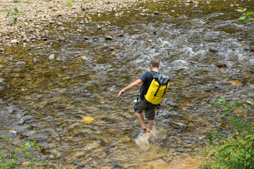 Hiking man crossing river