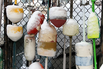 snow covered water buoys hanging on a chain link fence