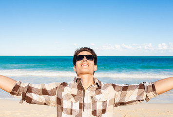 Happy young man standing on the beach.