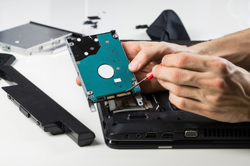 Cleaning old laptop PC. Hands of person performing maintenance on portable computer and cleaning connector contacts with screwdriver