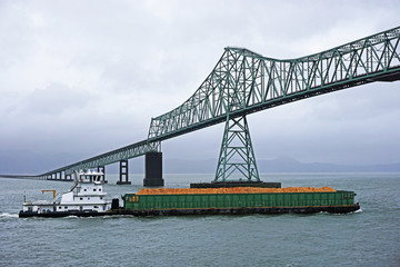 pusher tug and barge heading up the Columbia river and passing under the Astoria-Megler bridge