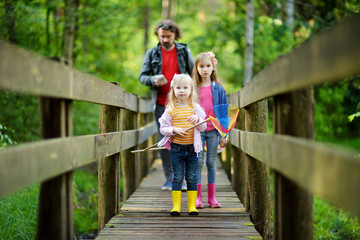Two cute little sisters hiking in a forest with their grandmother