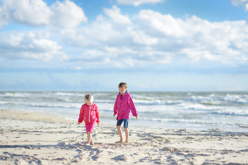 Two little sisters having fun on a sandy beach of Baltic sea