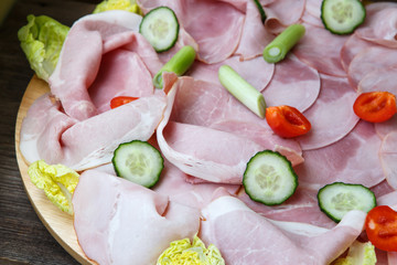 Food tray with delicious salami, pieces of sliced ham, tomatoes,