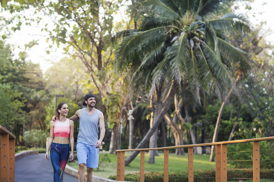 Happy Couple Walking On Road Against Trees At Park