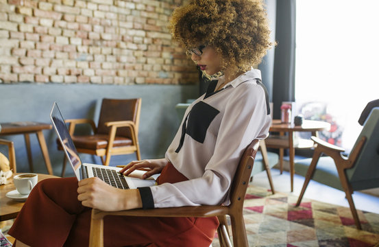 Side View Of Businesswoman Using Laptop In Hotel Lobby