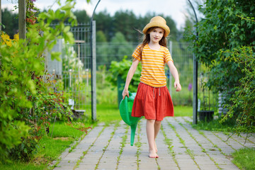 Cute little girl watering flowers in the garden