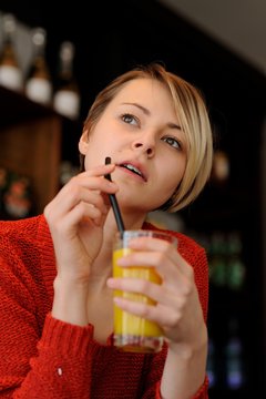 Attraktive, junge, blonde Frau mit Orangensaftglas