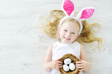 Cute little girl wearing bunny ears playing egg hunt on Easter © MNStudio