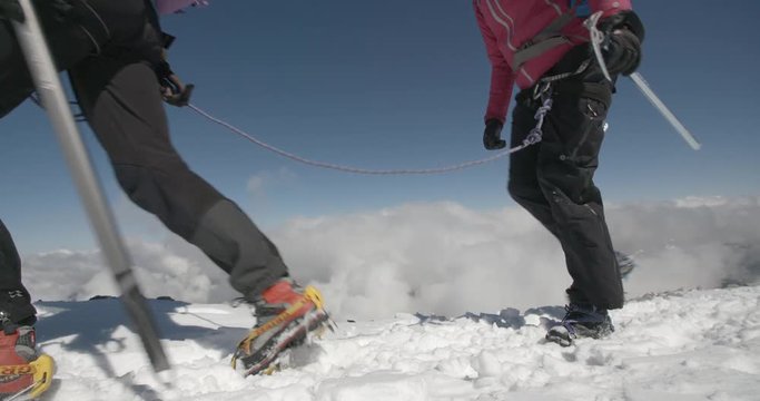Two Mountaineers Roped Together in Blue Sky Above the Clouds.