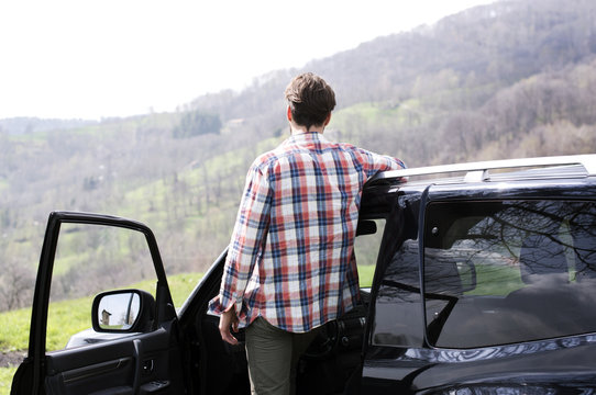 Rear View Of Man Standing Outside Car On Mountain