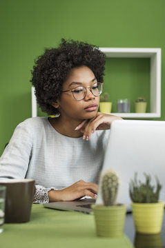 Serious woman using laptop computer having coffee at office