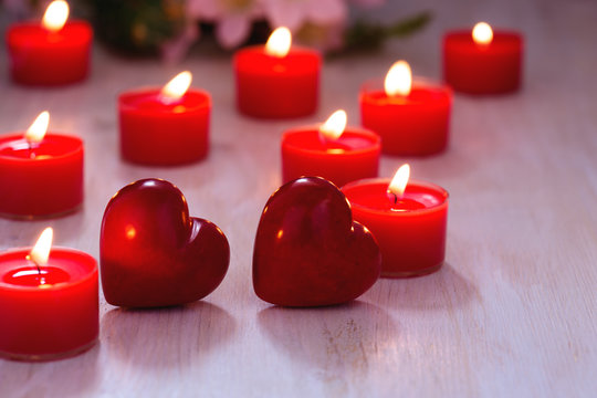 Two red hearts and burning candles on  table