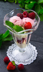 ice cream with berries of raspberry, strawberry and mint in a  glass against the background of a dark table. Closeup