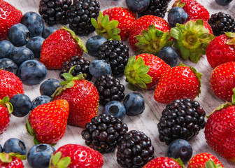 strawberries blackberries blueberries and mint arranged on the table