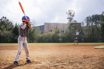 Side view of boy swinging baseball bat on field