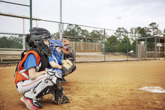 Side view of baseball catcher's crouching on field