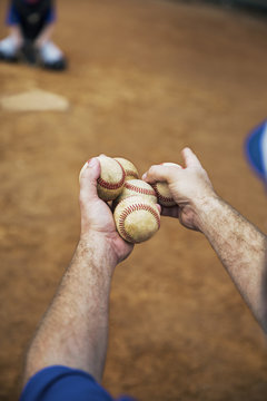 Cropped image of coach holding baseballs on field