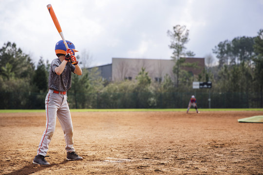 Side view of boy swinging baseball bat on field