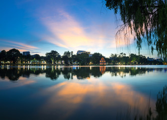 Hoan Kiem lake ( Ho Guom, Sword lake), the center of Hanoi capital, Vietnam at twilight. Willow branches on foreground