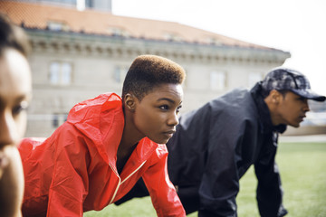 Determined female athlete doing push-ups with friends in city