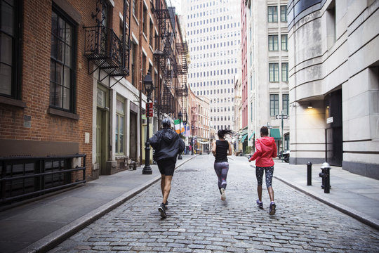 Rear view of multiethnic athletes running on city street