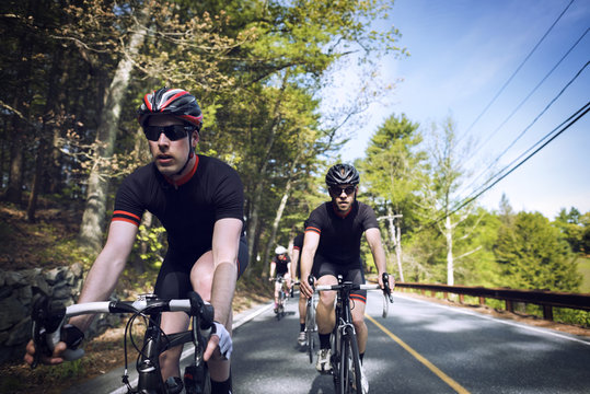 Determined male cyclists riding bicycles on country road