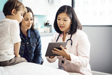 Doctor explaining report on tablet computer to family in clinic