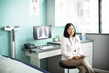 Portrait of happy female doctor sitting in clinic