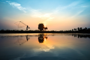 Fototapeta na wymiar Vietnamese rural countryside sunset scene with silhouette farmers carrying bamboo fish traps home