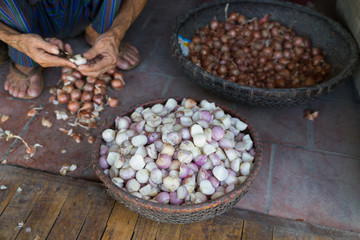 Basket of peeled onions. Old aged man hands peeling the onions on floor