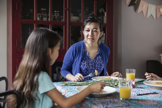 Mother talking to daughter while eating breakfast on birthday