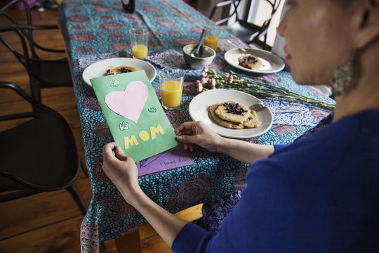 High angle view of woman holding greeting card on birthday at dining table