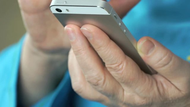 Woman's hand holding the silver mobile phone. Close up