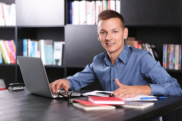 Obraz premium Handsome man with laptop studying in library