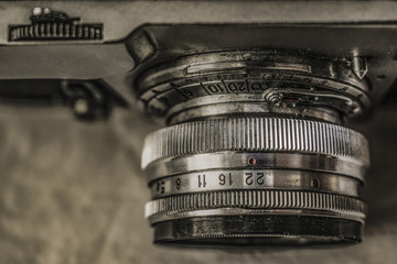 Close up view from above of old Russian analog film camera on dirty canvas with vintage look. On the camera, there can be seen aperture ring, focusing ring, lens, filter thread