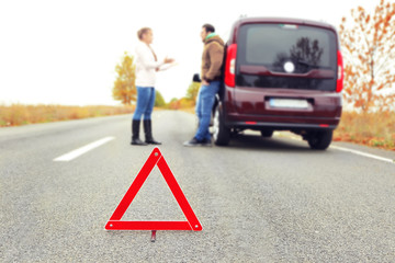 Traffic warning sign on road with car and couple on background