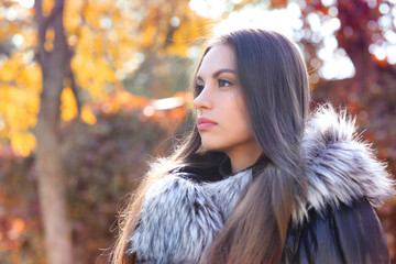 Beautiful young woman wearing coat with fur collar outdoors