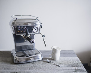 Espresso machine with coffee cups and spoon on table
