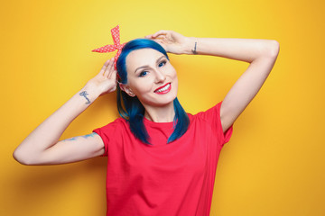 Beautiful young woman with stylish color hair and tattoo on yellow background