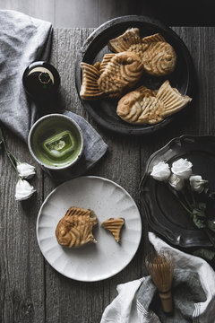 Overhead view of taiyaki with matcha tea and roses on wooden table