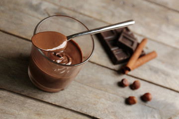 Chocolate mousse in glass with spoon on wooden background