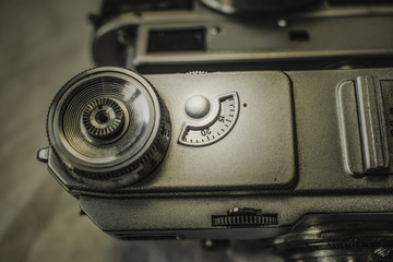 Close up view from above of old Russian analog film camera on dirty canvas with vintage look. On the camera, there can be seen shutter release and shutter speed knobs