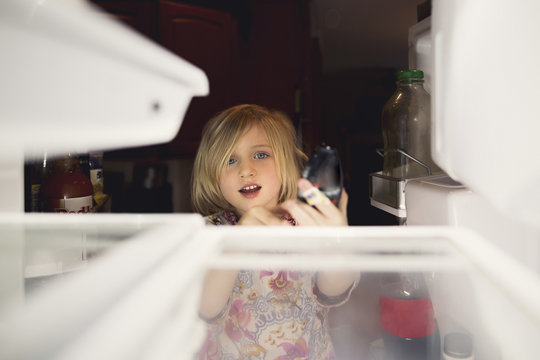 Cute girl looking into refrigerator at home