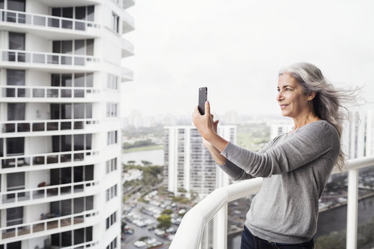 Mature woman taking selfie on balcony - Powered by Adobe