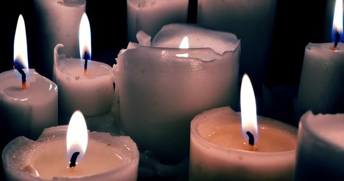 Close up 4K view of wax candles burning quietly in darkness. Abstract background
