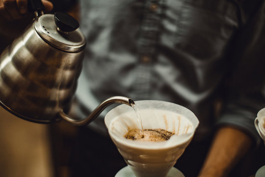 Midsection of barista pouring water in coffee filter at cafe - Powered by Adobe